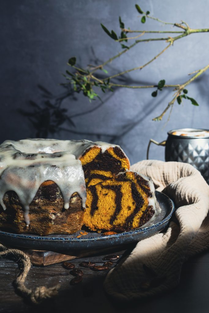 Kürbis-Marmorkuchen als Gugelhupf mit Glasur in dunklem Ambiente fotografiert
