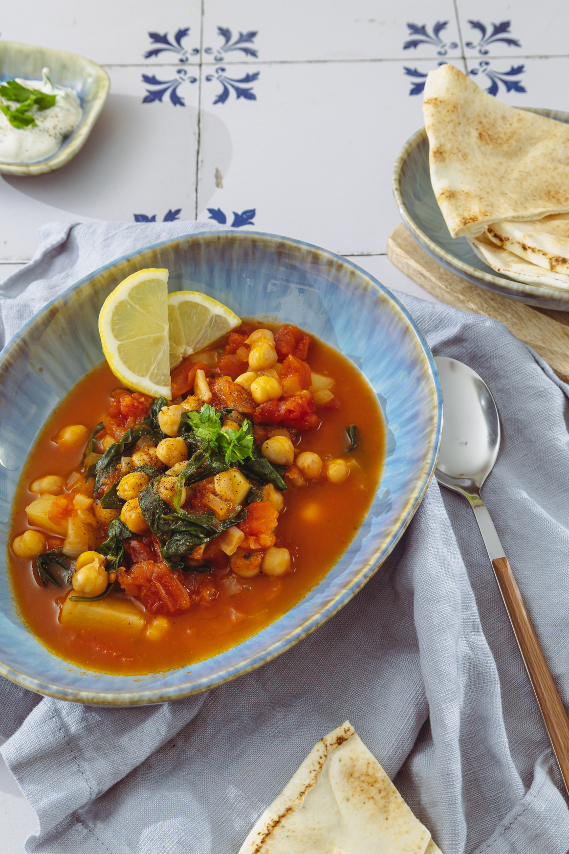 Kichererbseneintopf in hellblauer Schale mit Zitronenscheiben